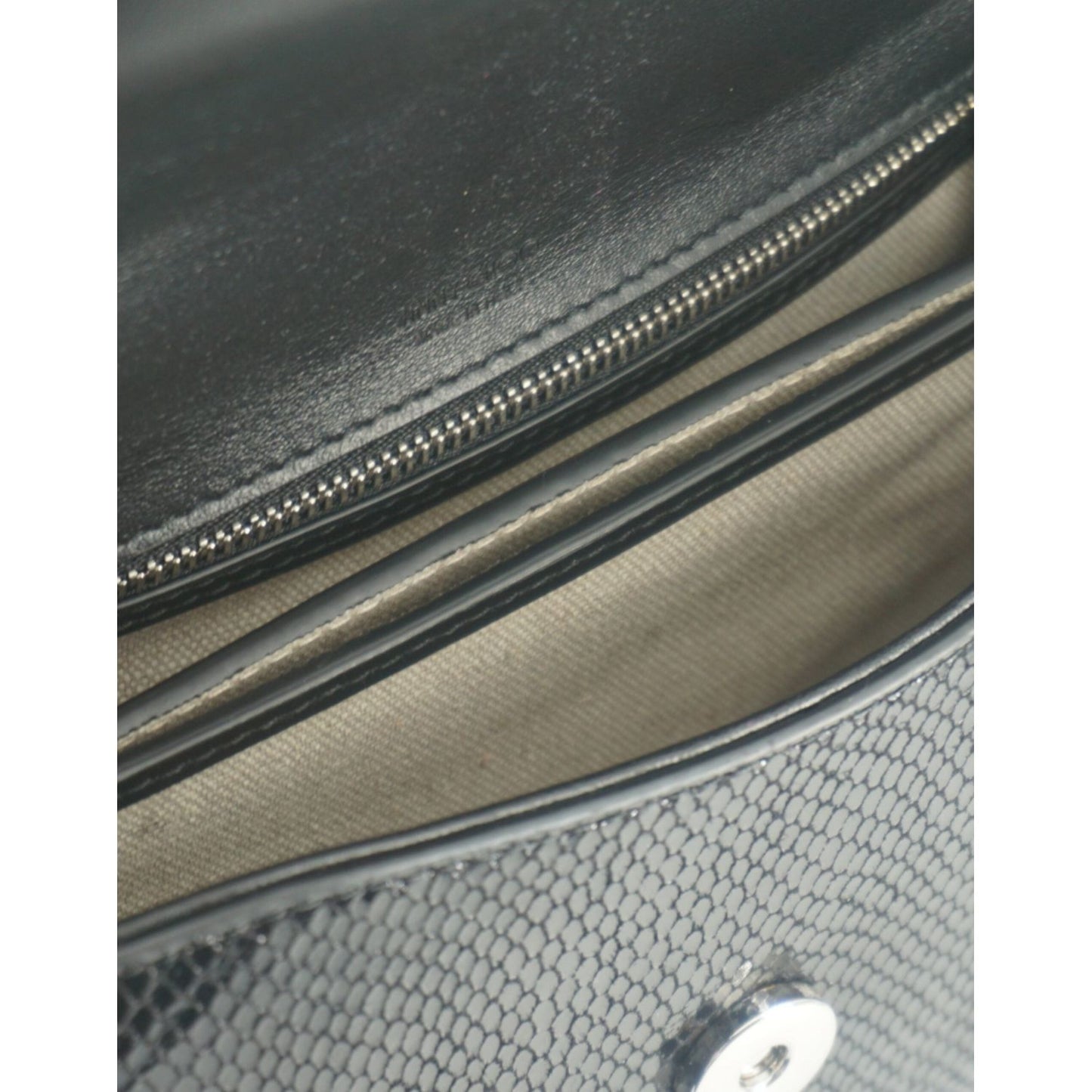Interior view of Jimmy Choo black leather shoulder bag with lizard print, showcasing compartments and zip pocket detail.