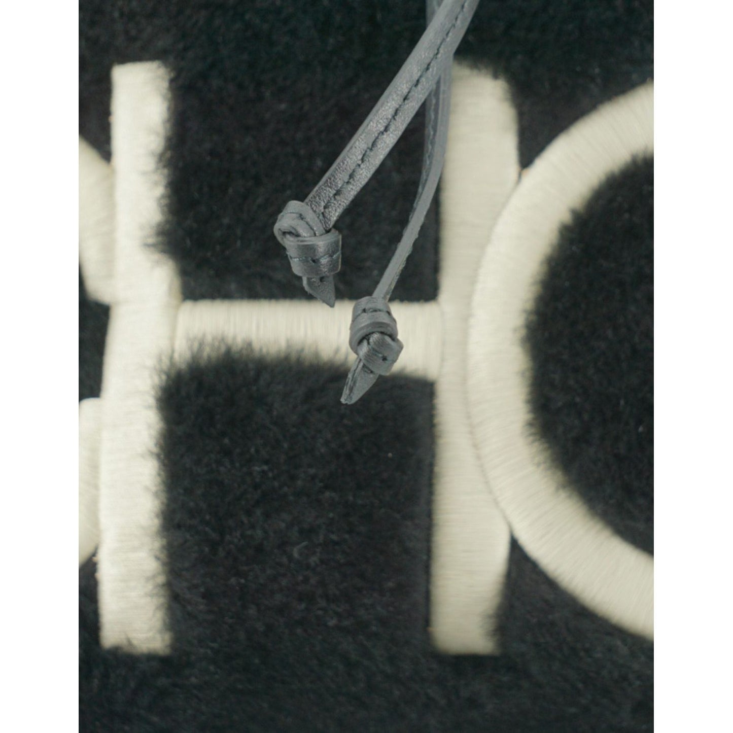 Close-up of Jimmy Choo black leather and fabric bag with white logo detailing, featuring leather and fabric texture.