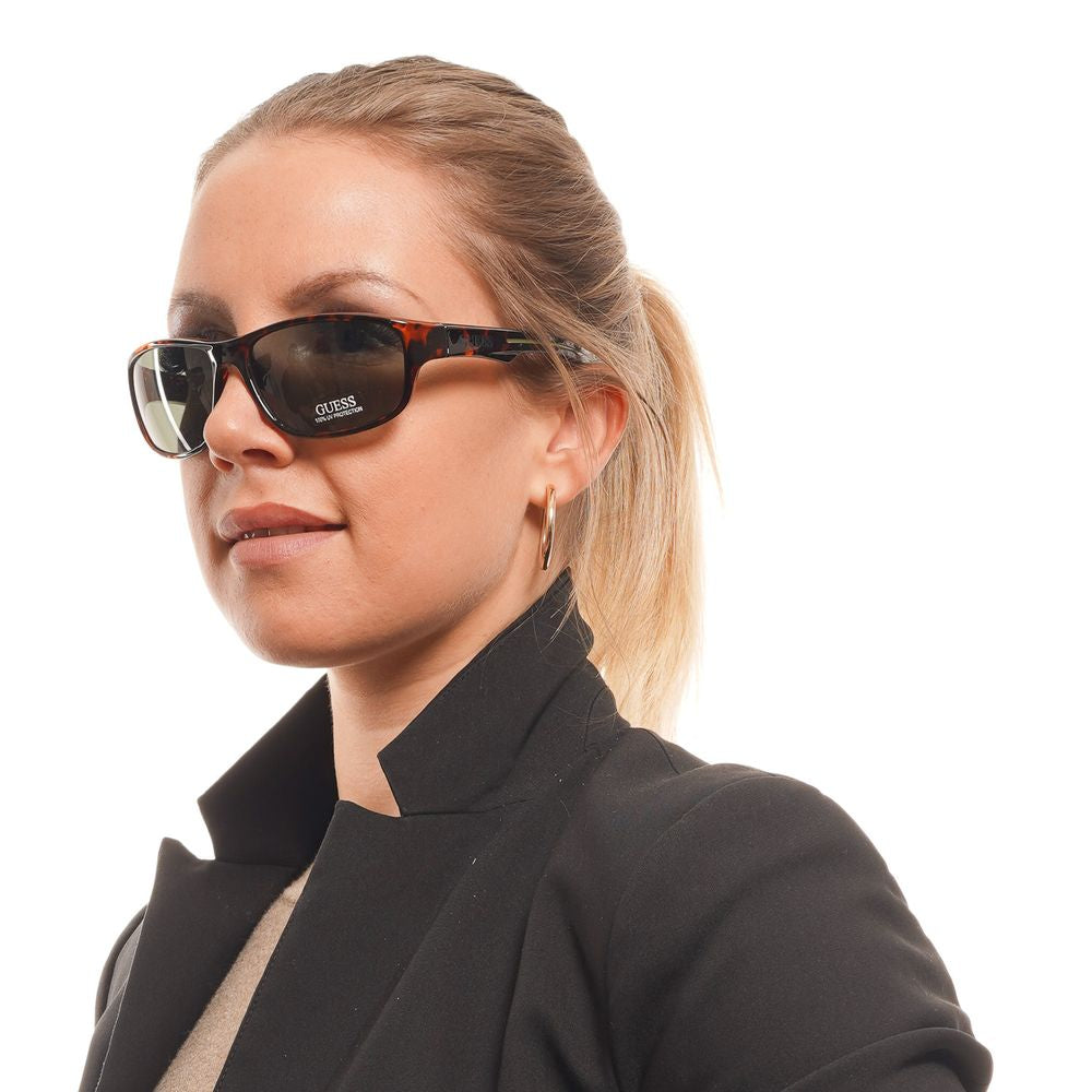 Unisex Guess brown sunglasses with green lenses, worn by a person, offering 100% UVA & UVB protection, full-rim plastic frame.