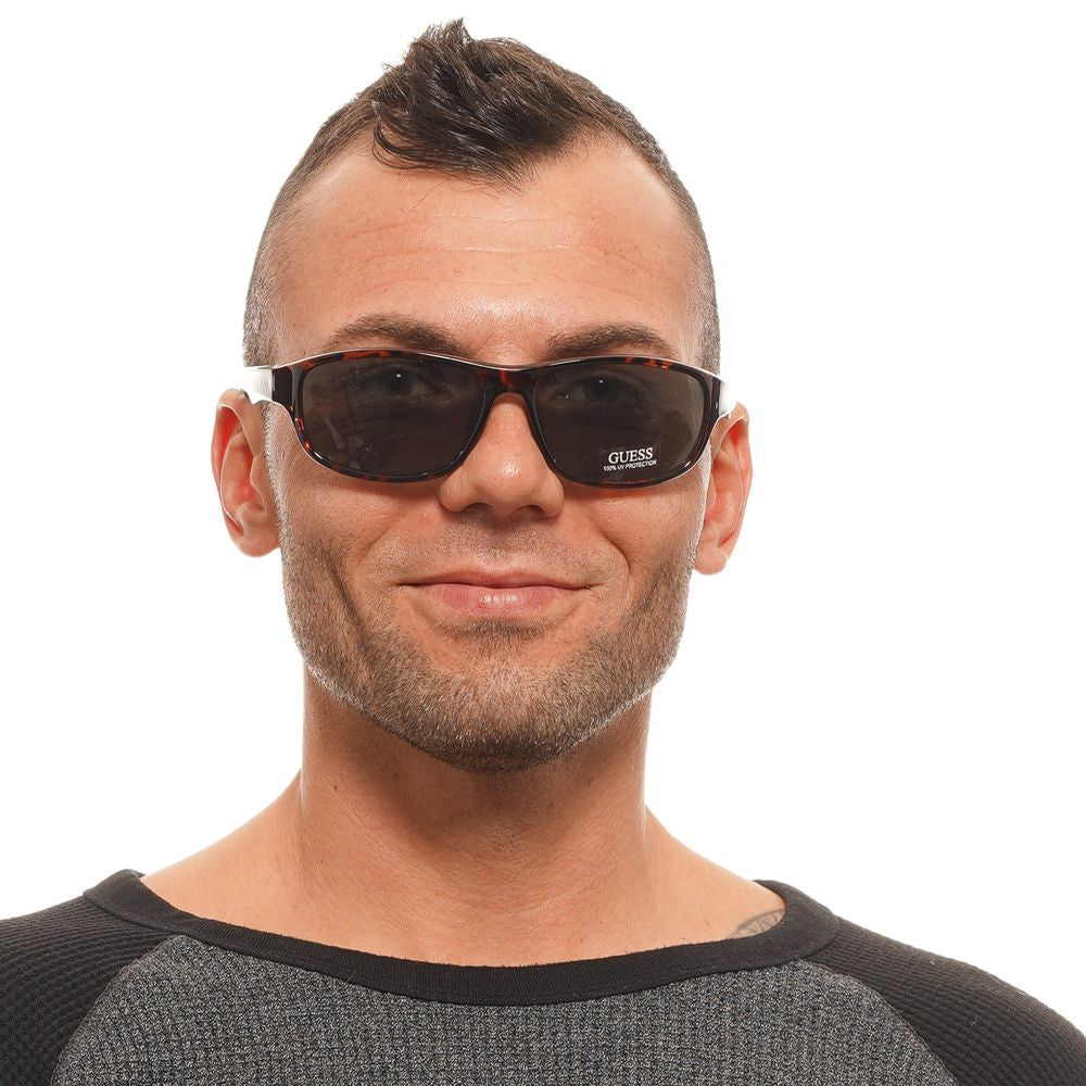 Alt Tag: Person wearing Guess brown unisex sunglasses with green lenses, plastic frame, full-rim style, 100% UVA & UVB protection.