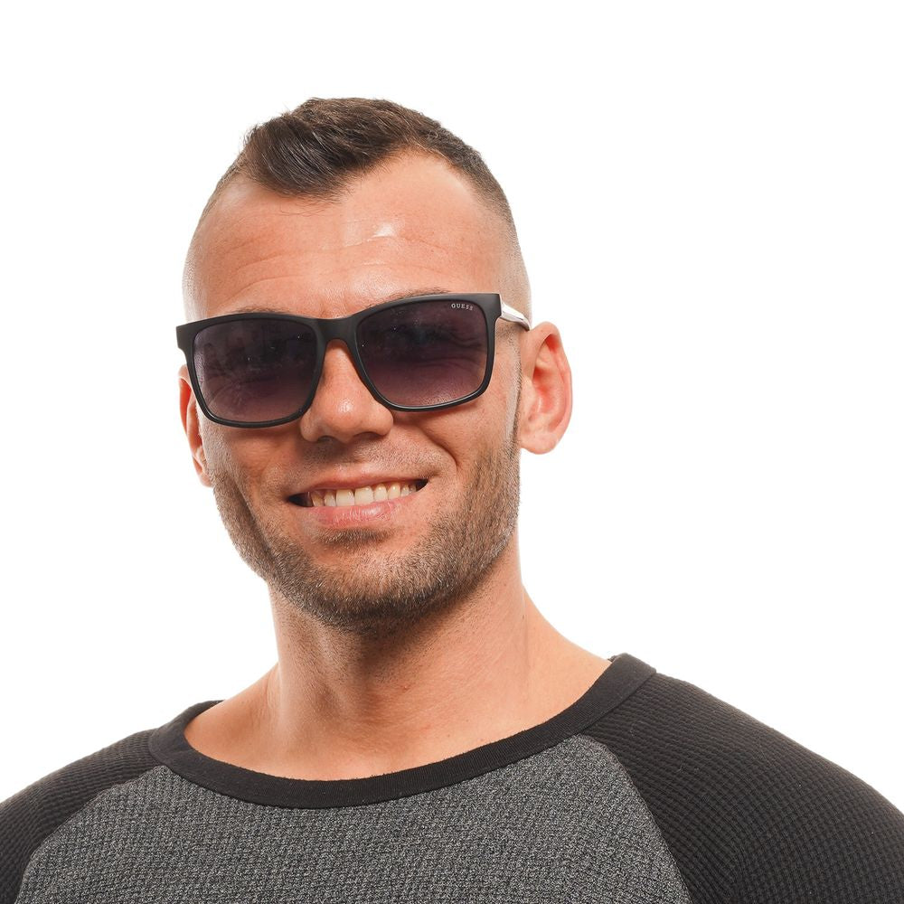 Man wearing Guess black square sunglasses with gradient grey lenses and full-rim black plastic frame.