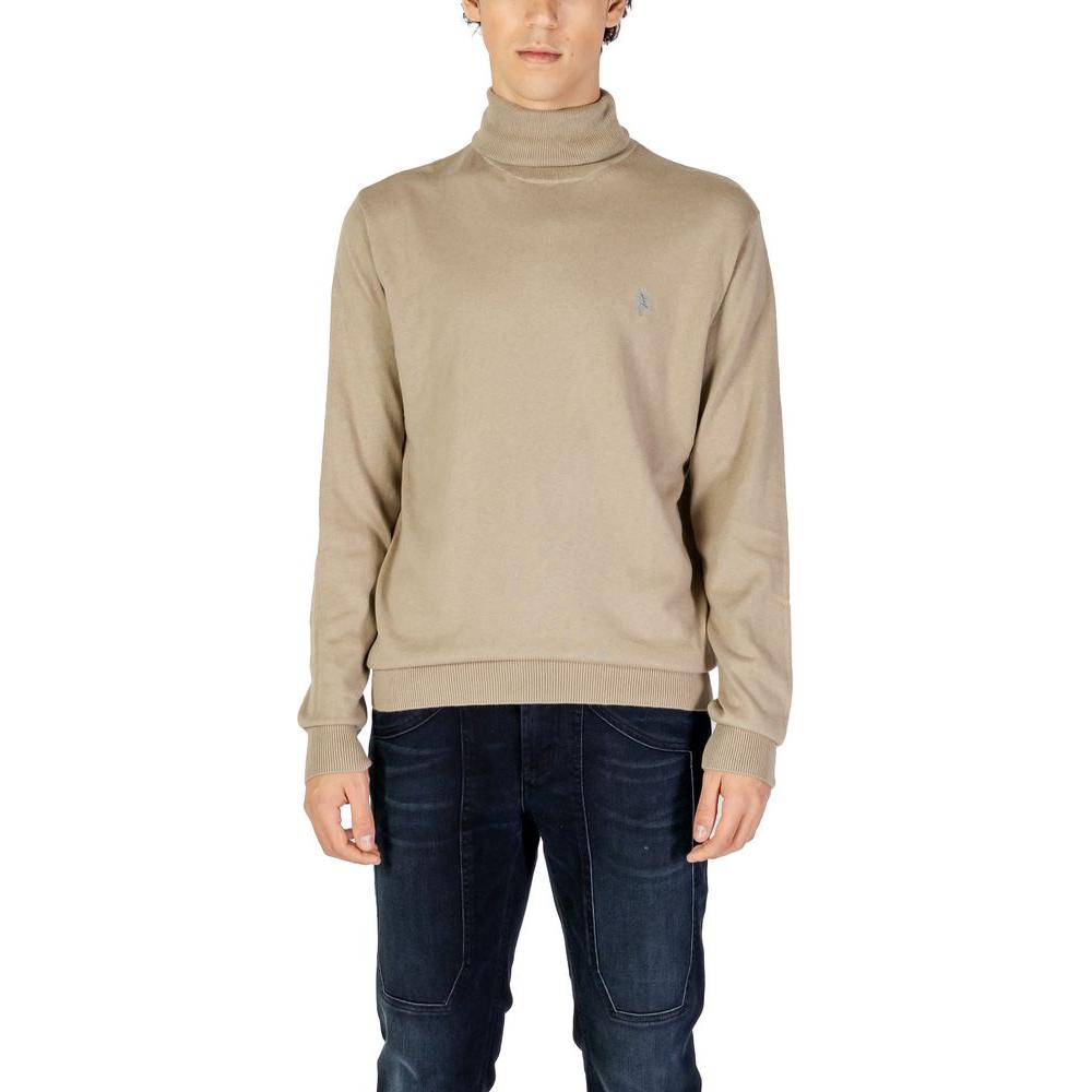 Man wearing U.S. Polo Assn. beige cotton turtleneck sweater with embroidered logo, perfect for formal and casual occasions.