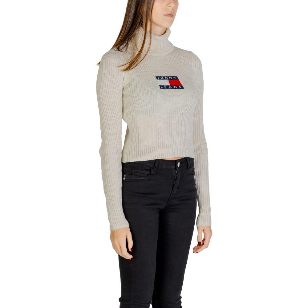 Woman wearing Tommy Hilfiger beige sweater made of recycled polyester, featuring logo, fall/winter collection.