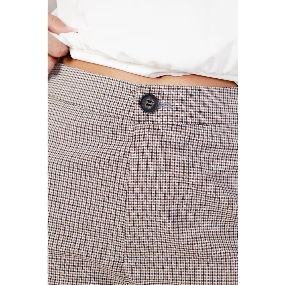Close-up of women's beige cigarette pants in polyester blend, featuring button detail, from the Autumn/Winter collection.