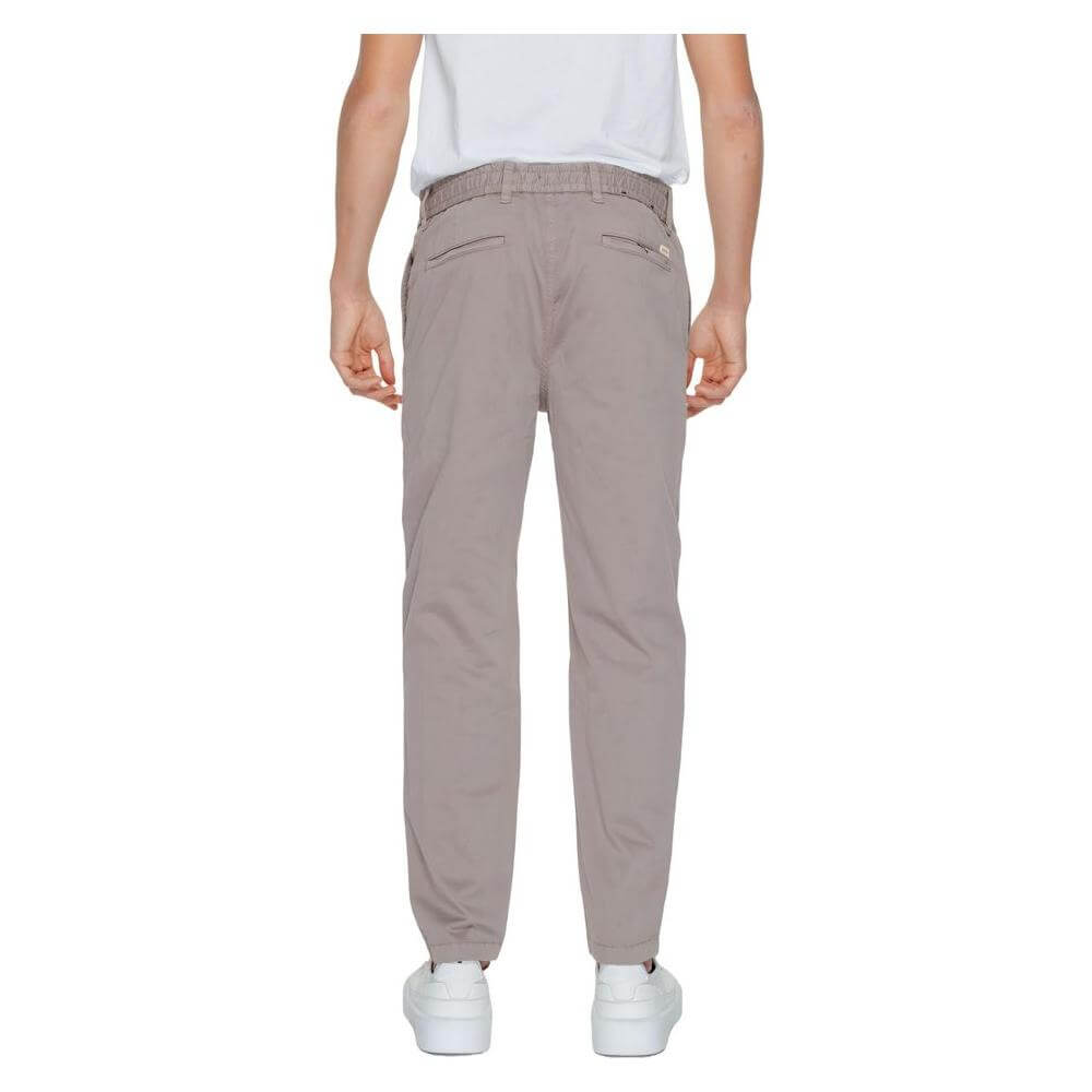 Back view of Hugo Boss brown men's tapered trousers, cotton-elastane blend, from the Spring/Summer collection, worn by a model.