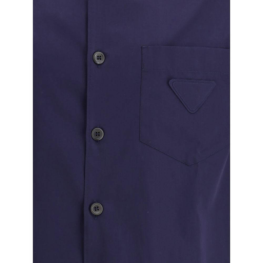 Prada short-sleeved cotton shirt featuring buttons and front patch pocket with iconic triangular brand patch, ideal for summer elegance.