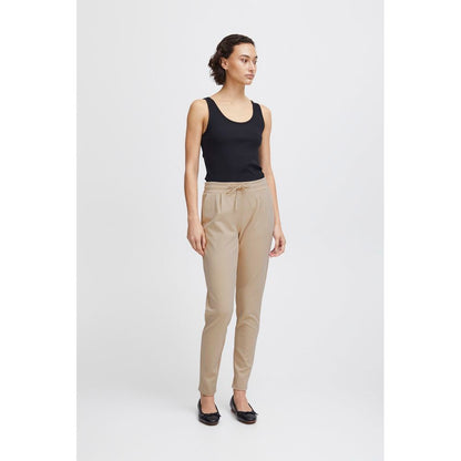 Model wearing ICHI Beige Polyester Pants, mid-rise with drawstring, showcasing slim fit and modern style for women's fashion.
