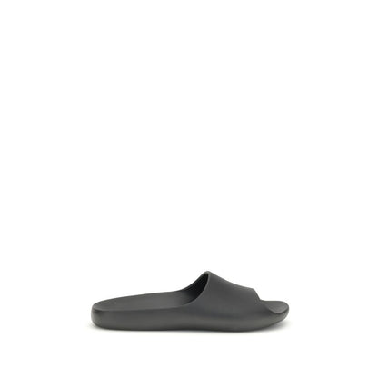 The Row Black Rubber Slippers featuring minimalistic design with contoured footbed for comfort, seamless construction, and lightweight feel.