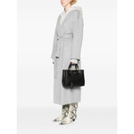 Woman holding Emporio Armani MyEA small shopping bag in black faux leather with gold-tone hardware, styled with gray coat and snake-print boots.
