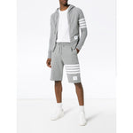 Model wearing Thom Browne Shorts Light Grey with signature 4-Bar stripe and elasticated waistband, styled with hoodie and sneakers.